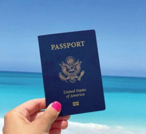 holding-passport-in-hand-at-beach-image-traveling-ears-vacations-300x276