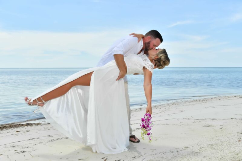 Sandals Curaçao Infinity Pool Group Trip Couple sharing a romantic kiss during their vow renewal on the beach at Sandals South Coast in Jamaica.