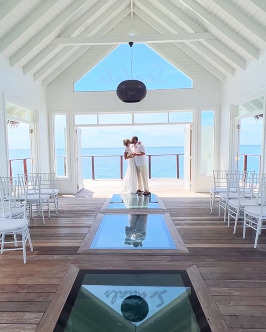 Couple sharing a romantic kiss during their vow renewal on the beach at Sandals South Coast in Jamaica
