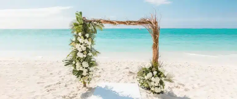 Beach wedding venue setup in Turks and Caicos with floral arch and ocean view