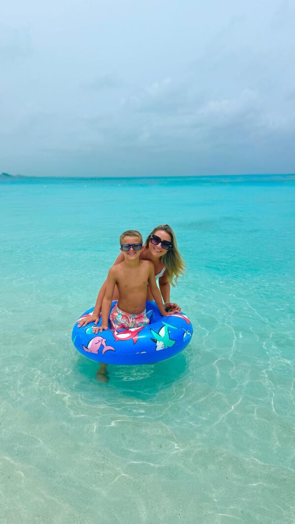Mother and son enjoying a sunny day at Grace Bay Beach during a June 2025 family vacation at Beaches Turks and Caicos Resort. They're smiling on a colorful float in crystal-clear turquoise water.