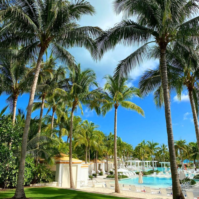 Palm trees framing a luxury pool with lounge chairs at the Grand Hyatt Baha Mar resort in Nassau, Bahamas.