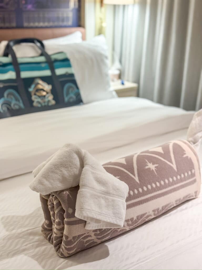 A towel animal shaped like an elephant placed on a bed inside a Disney Cruise Line stateroom.