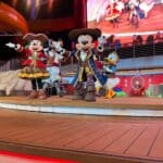 Mickey Mouse, Minnie Mouse, and Disney characters dressed as pirates performing during Pirate Night on the Disney Treasure cruise ship.