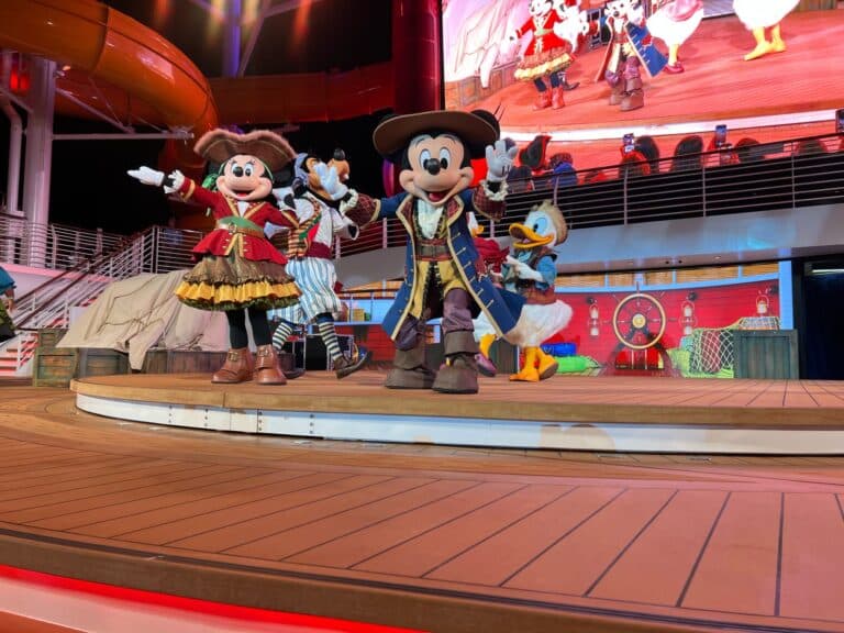 Mickey Mouse, Minnie Mouse, and Disney characters dressed as pirates performing during Pirate Night on the Disney Treasure cruise ship.