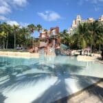 Tropical water park at Atlantis Bahamas with slides, splash zones, and palm trees under a bright blue sky.