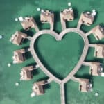 A breathtaking aerial drone view of the heart-shaped overwater bungalows at Sandals South Coast in Jamaica, surrounded by calm turquoise waters, perfect for a luxury Caribbean honeymoon or romantic getaway.