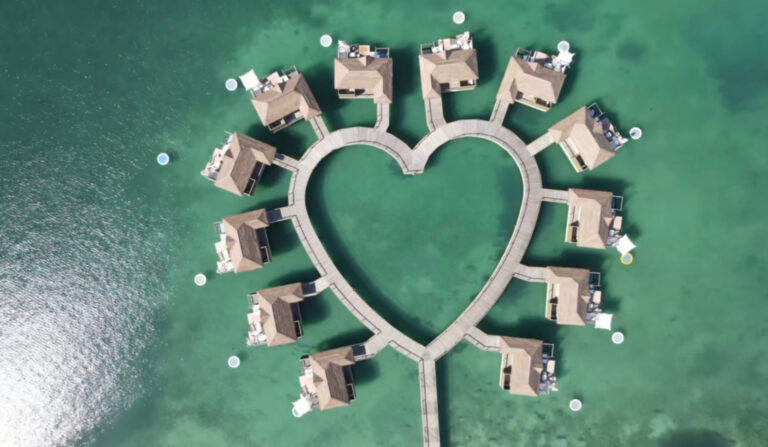 A breathtaking aerial drone view of the heart-shaped overwater bungalows at Sandals South Coast in Jamaica, surrounded by calm turquoise waters, perfect for a luxury Caribbean honeymoon or romantic getaway.