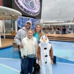 Family on the top deck of the Disney Wonder during the Frozen deck show in Alaska, with their son dressed as Olaf and the ship’s giant screen in the background.