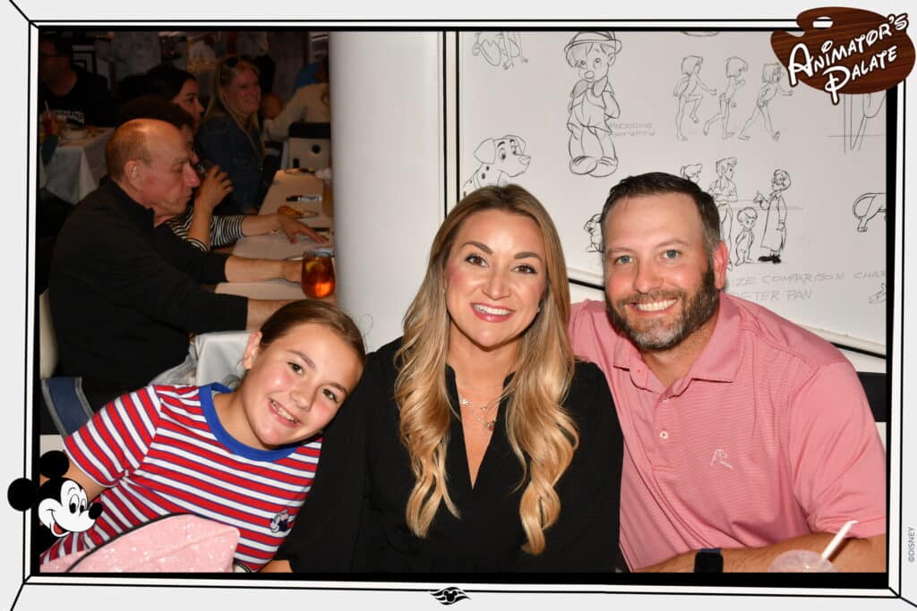 Family smiling together at Animator’s Palate aboard the Disney Wonder, with Disney character sketches on the walls in the background during a Disney Alaska Cruise.