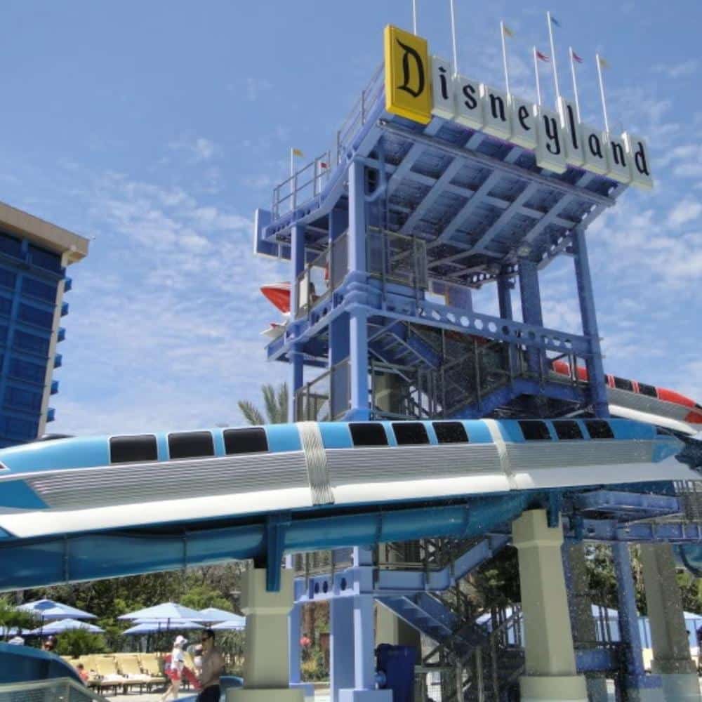 Pool area at Disneyland Hotel featuring monorail-themed water slides, palm trees, and family-friendly swimming areas at the Disneyland Resort