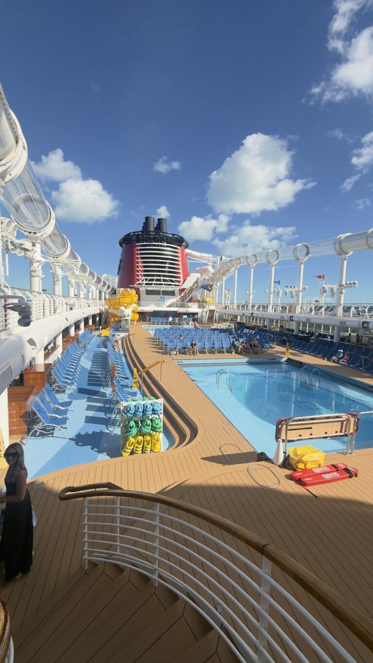 Disney Cruise Line pool deck with pools, lounge chairs, and ocean views onboard.