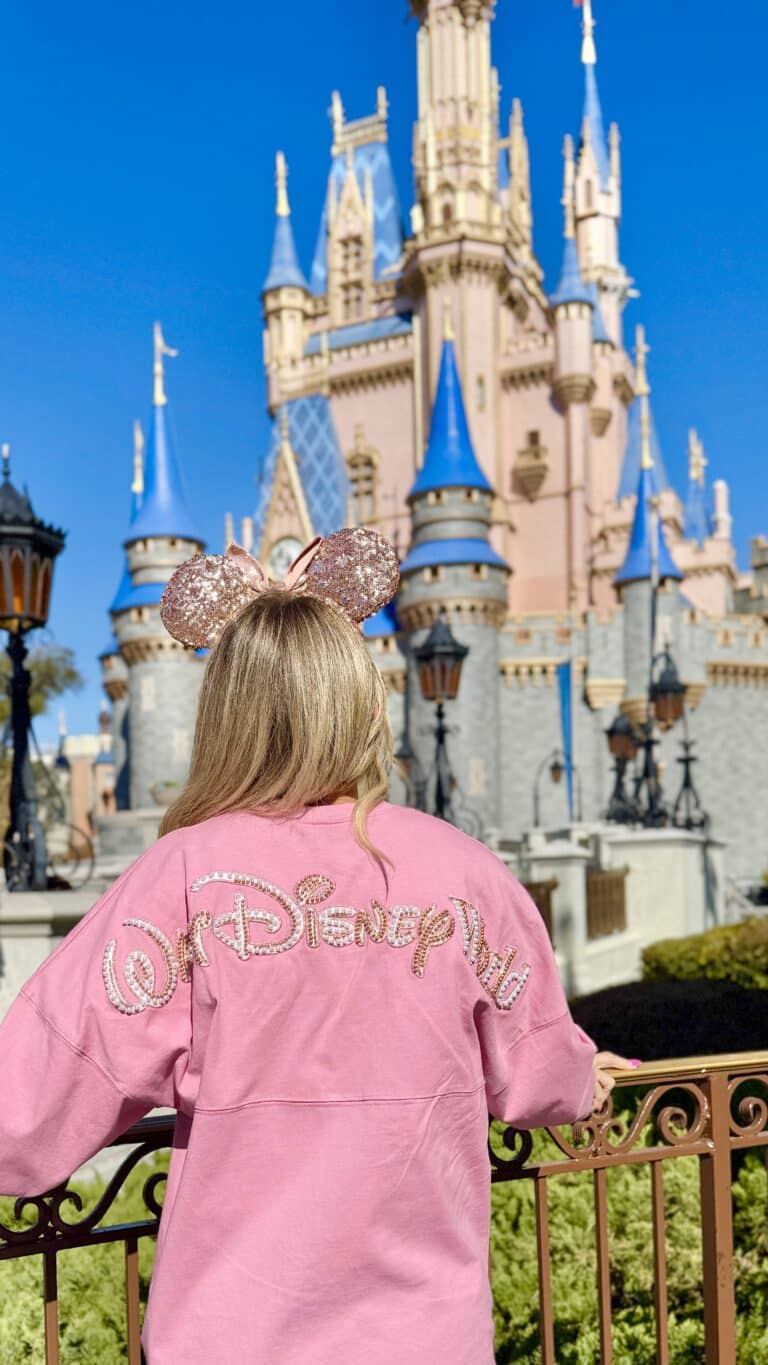 Cinderella Castle at Magic Kingdom with guest wearing Minnie ears at Disney World.
