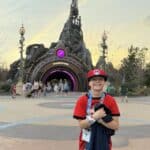 Child standing in front of Epic Universe portal at Universal Orlando theme park at sunset.