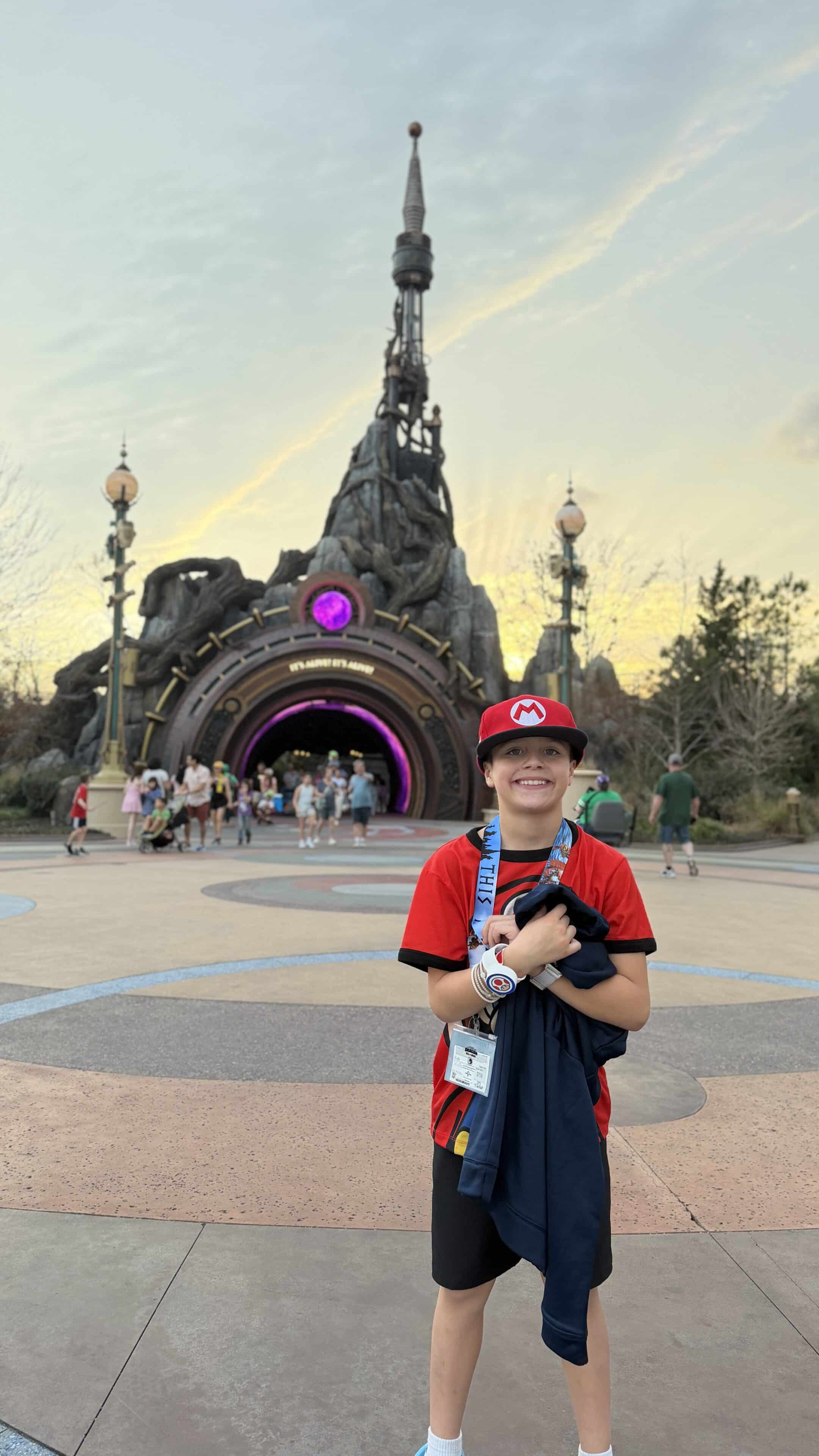 Child standing in front of Epic Universe portal at Universal Orlando theme park at sunset.