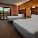Disney’s Animal Kingdom Lodge guest room with warm African-inspired decor, wood furnishings, private balcony, and views of lush savanna or resort grounds at Walt Disney World Resort
