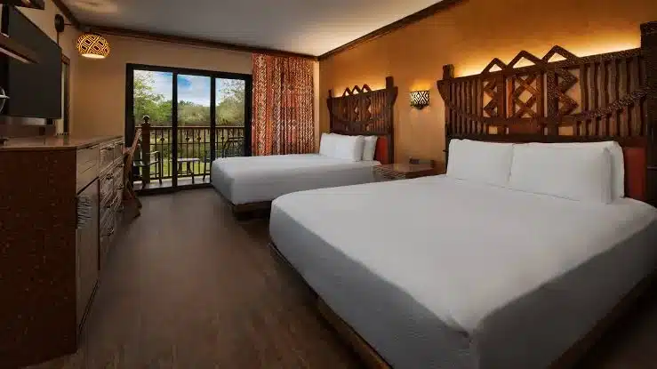 Disney’s Animal Kingdom Lodge guest room with warm African-inspired decor, wood furnishings, private balcony, and views of lush savanna or resort grounds at Walt Disney World Resort