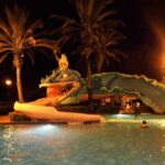 Disney’s Port Orleans French Quarter pool featuring Doubloon Lagoon with a whimsical sea serpent water slide, Mardi Gras theming, colorful aquatic play area, and lush tropical surroundings at Walt Disney World Resort