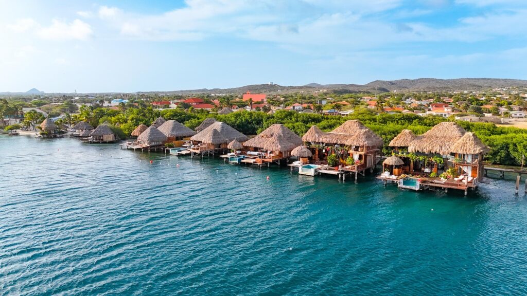 Aerial view of Aruba Ocean Villas overwater bungalows along the turquoise Caribbean shoreline in Savaneta, Aruba