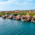 Aerial view of Aruba Ocean Villas overwater bungalows along the turquoise Caribbean shoreline in Savaneta, Aruba