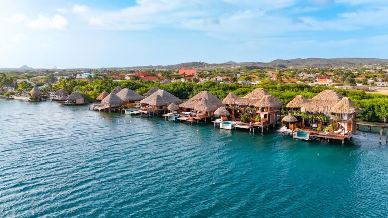 Aerial view of Aruba Ocean Villas overwater bungalows along the turquoise Caribbean shoreline in Savaneta, Aruba