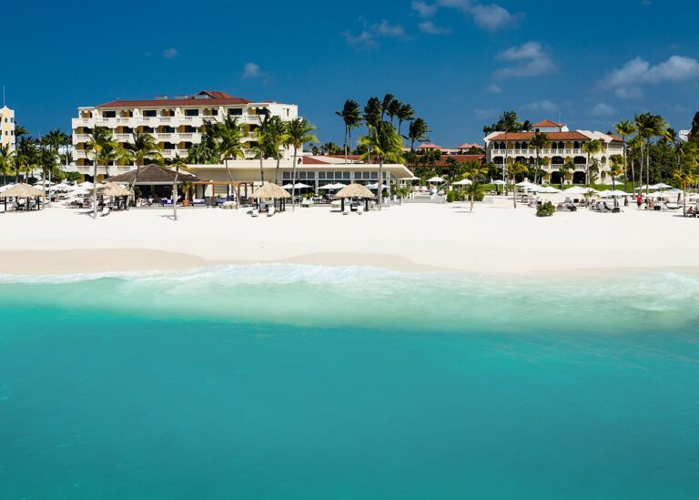 Bucuti & Tara Beach Resort buildings and palms behind white sand and turquoise water on Eagle Beach Aruba