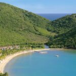Aerial view of Carlisle Bay Antigua resort along a sheltered beach between lush green hills and blue Caribbean water