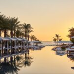 Sunset over the reflective resort pool, cabanas and palm trees at Chileno Bay Resort in Los Cabos, Mexico