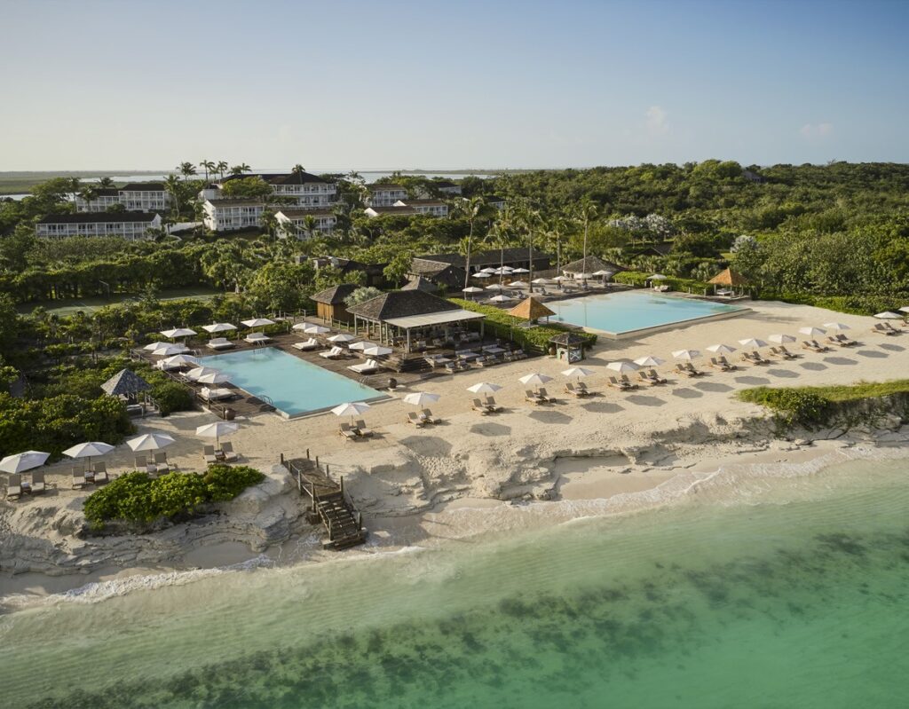 Aerial view of COMO Parrot Cay with beachfront pools, white sand and turquoise water in Turks and Caicos