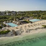 Aerial view of COMO Parrot Cay with beachfront pools, white sand and turquoise water in Turks and Caicos