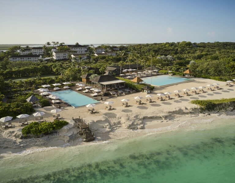 Aerial view of COMO Parrot Cay with beachfront pools, white sand and turquoise water in Turks and Caicos