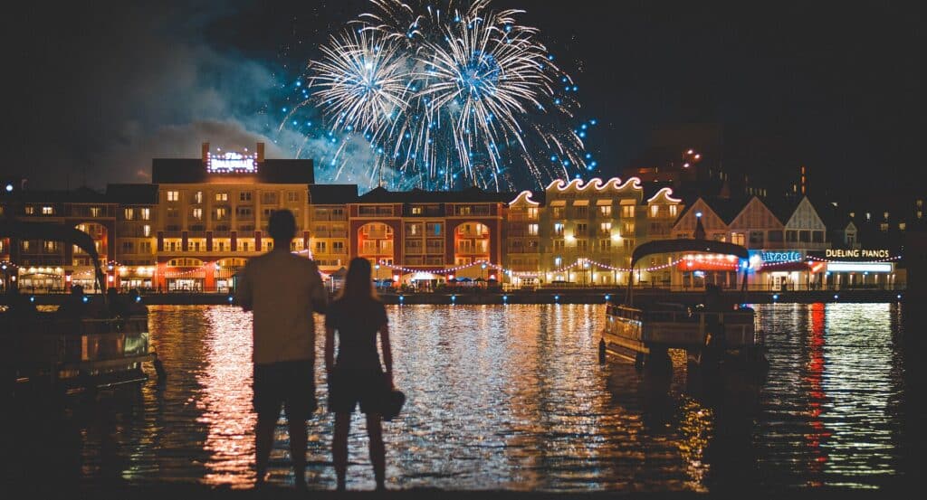 Disney's BoardWalk Resort illuminated at night with fireworks over Crescent Lake