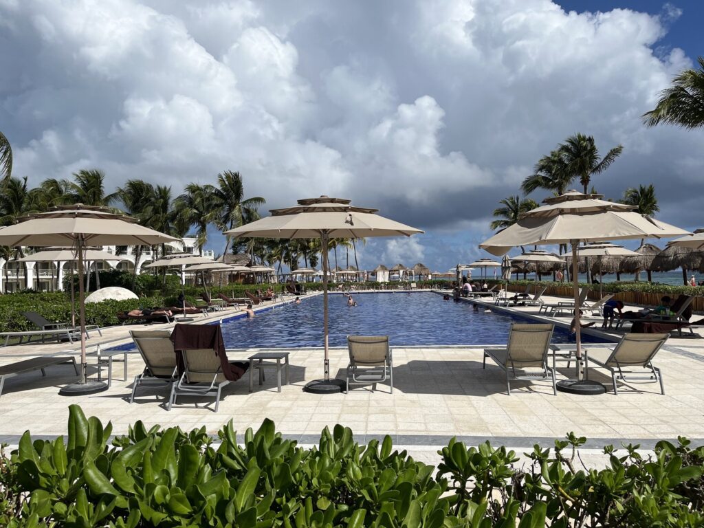 Main pool at Dreams Tulum Resort & Spa with loungers, palm trees and the Caribbean beach beyond