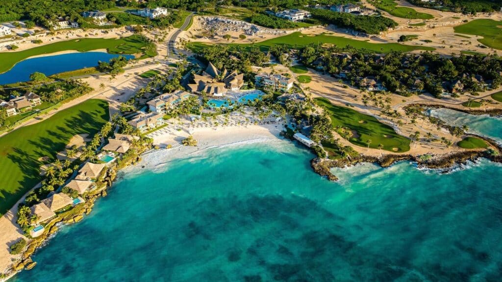 Aerial view of Eden Roc Cap Cana with resort buildings, pools, beach, turquoise water and golf landscape