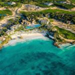 Aerial view of Eden Roc Cap Cana with resort buildings, pools, beach, turquoise water and golf landscape