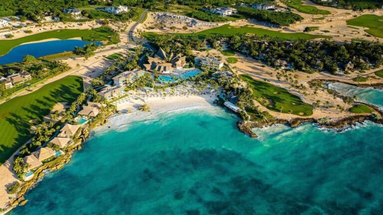 Aerial view of Eden Roc Cap Cana with resort buildings, pools, beach, turquoise water and golf landscape
