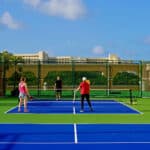 Pickleball courts with the beachfront resort behind at Kempinski Hotel Cancún, formerly The Ritz-Carlton Cancun