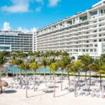 Garza Blanca Cancun resort towers, palm-lined pool deck, white sand and turquoise Caribbean water