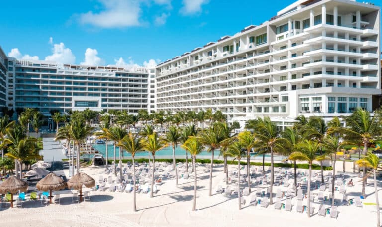 Garza Blanca Cancun resort towers, palm-lined pool deck, white sand and turquoise Caribbean water