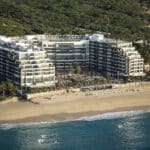 Aerial view of Garza Blanca Los Cabos resort buildings and pools along the sandy Pacific coastline