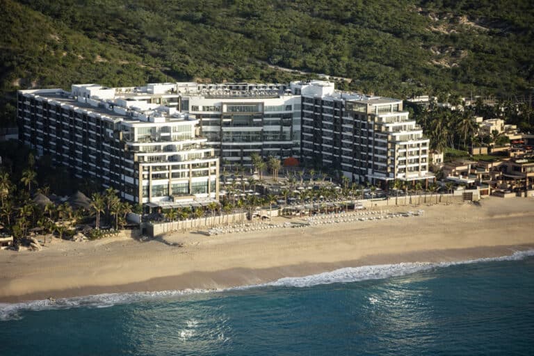 Aerial view of Garza Blanca Los Cabos resort buildings and pools along the sandy Pacific coastline
