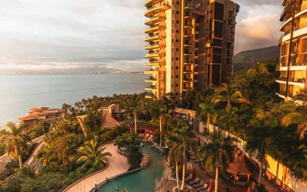 Garza Blanca Puerto Vallarta resort tower and tropical pool overlooking Banderas Bay at golden hour