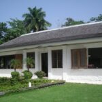 White single-story villa with wooden shutters and tropical landscaping at the GoldenEye estate in Jamaica
