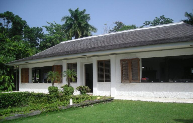 White single-story villa with wooden shutters and tropical landscaping at the GoldenEye estate in Jamaica