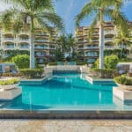Turquoise resort pool framed by palms and luxury guest buildings at Grace Bay Club in Turks and Caicos