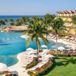 Grand Velas Riviera Maya pool, palm trees and oceanfront resort buildings