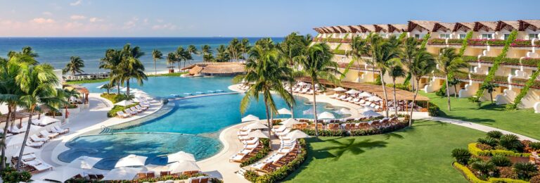 Grand Velas Riviera Maya pool, palm trees and oceanfront resort buildings