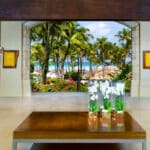 Open-air lobby at Hyatt Regency Aruba framing palm trees and tropical resort grounds toward Palm Beach
