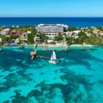 Aerial view of Impression Isla Mujeres by Secrets above turquoise Caribbean water and the resort pier