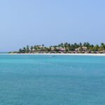 Jumby Bay Island resort buildings and palms viewed across vivid turquoise Caribbean water in Antigua